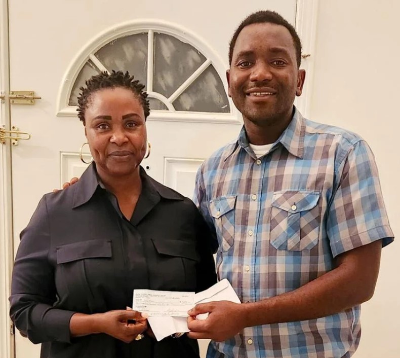 Fr. Denning Achidi delivers a check to Ms. Sally Mbah. An effort by some Genesee and Wyoming County church members helped provide beds for children in Achidi’s native Cameroon.